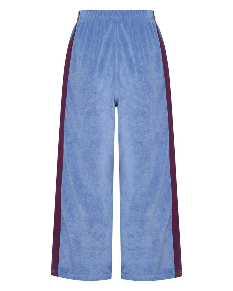 Blue terry towelling pants with purple side stripes on a white background