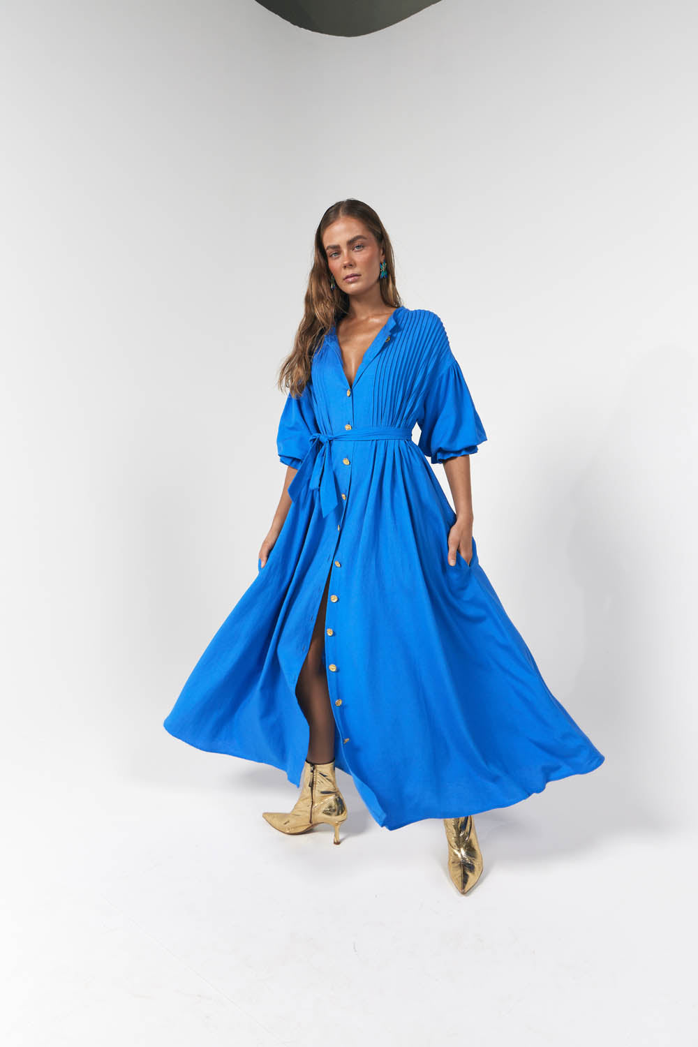Model wearing blue maxi dress with gold buttons and puff sleeves