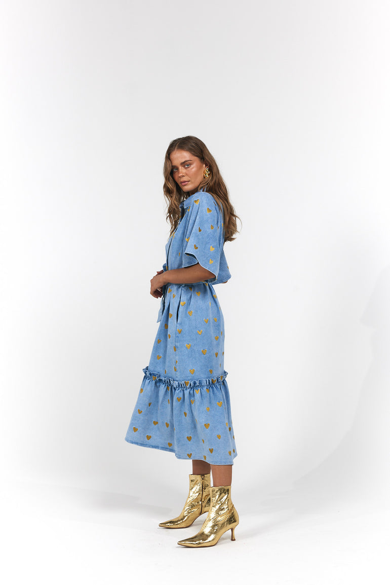 Woman wearing a blue denim dress with gold hearts and gold boots