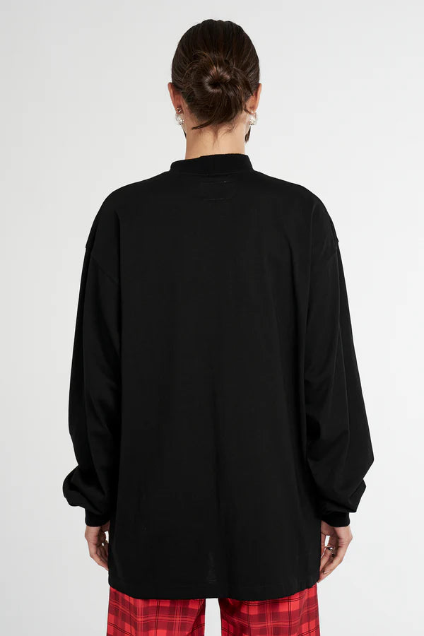 Person wearing a black long-sleeve Summi Summi top with red plaid pants on a white background