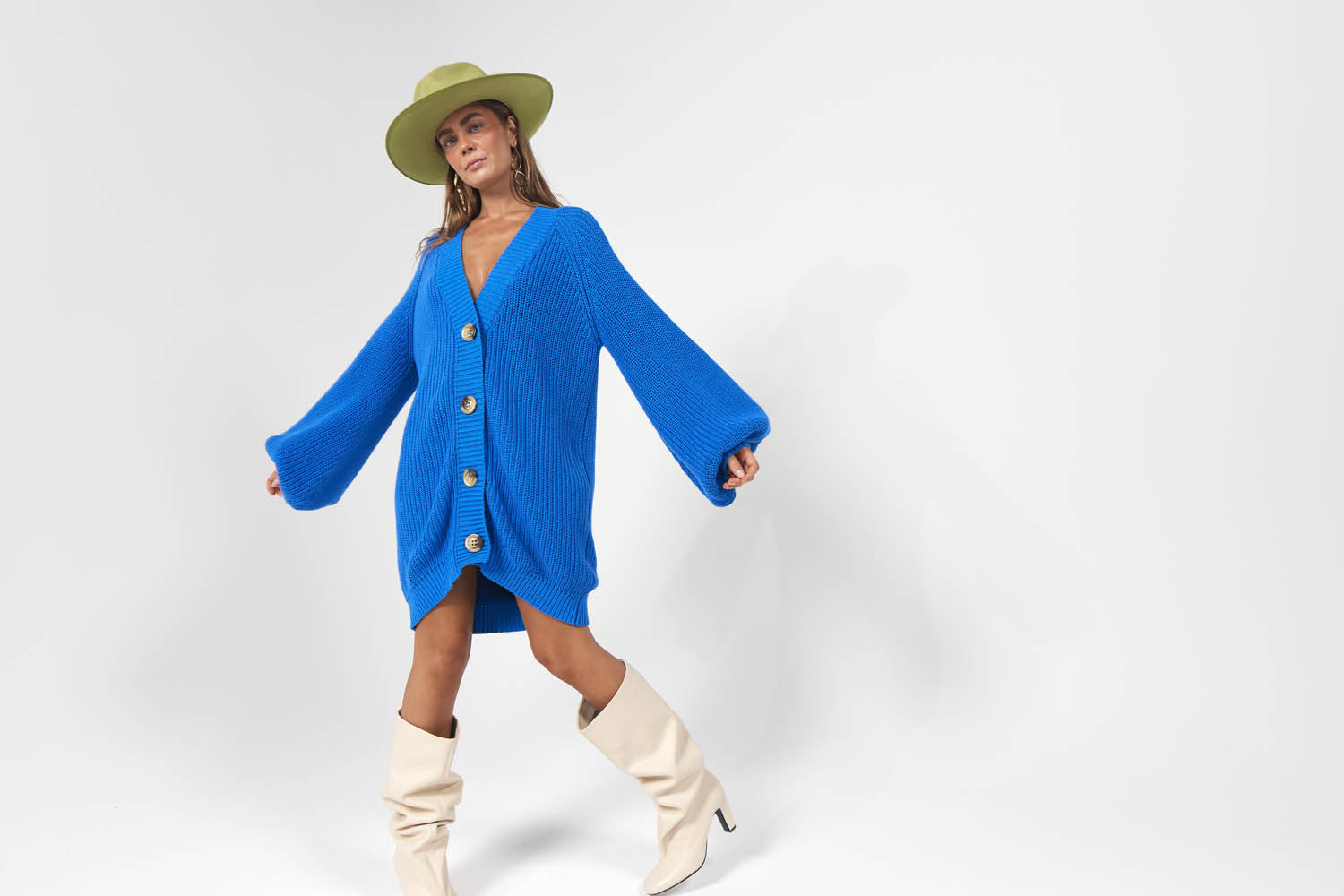 Model wearing oversized blue knitted cardigan, with big buttons down the front and billow sleeves.