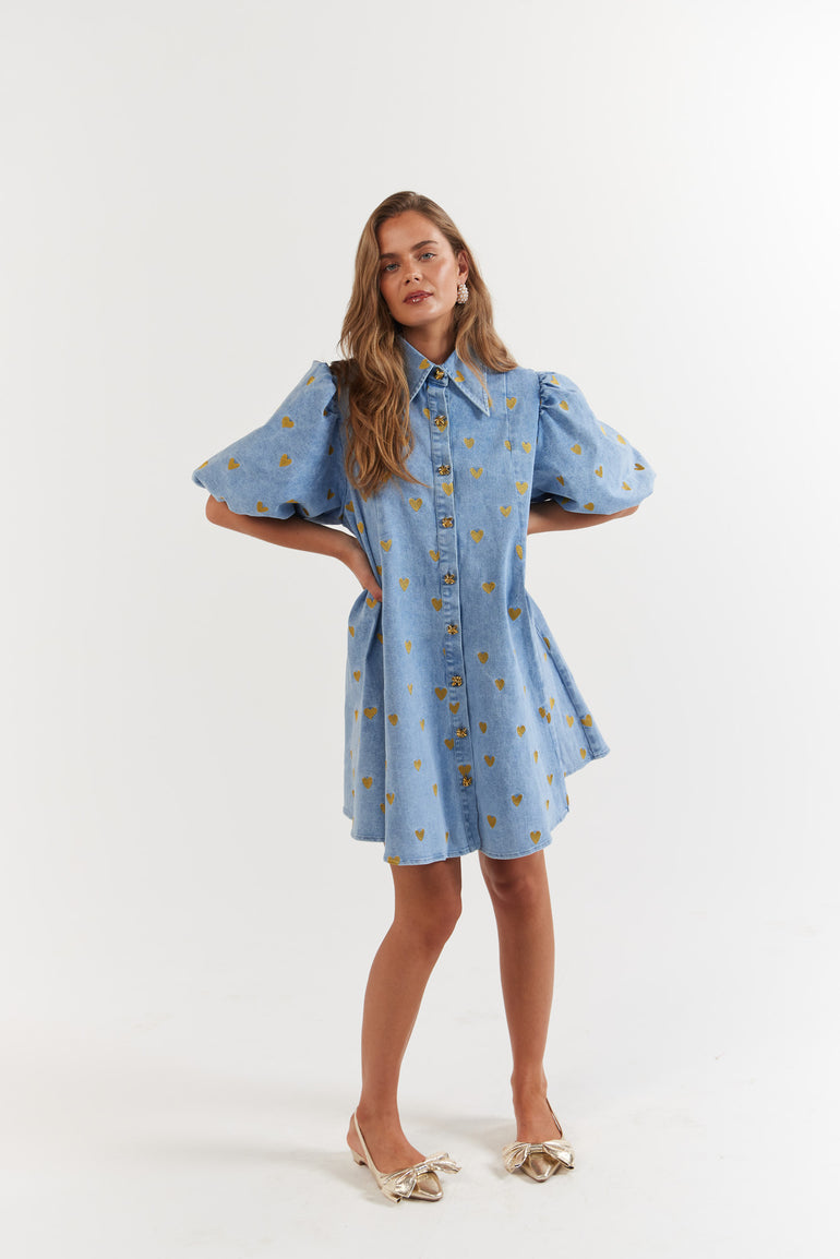Woman wearing a blue denim dress with gold hearts