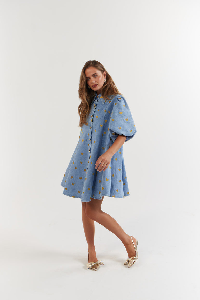 Woman wearing a blue denim dress with gold hearts