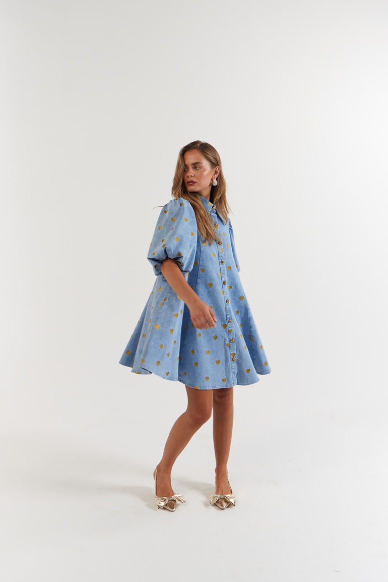 Woman wearing a blue denim dress with gold hearts