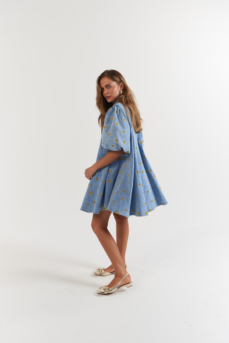 Woman wearing a blue denim dress with gold hearts