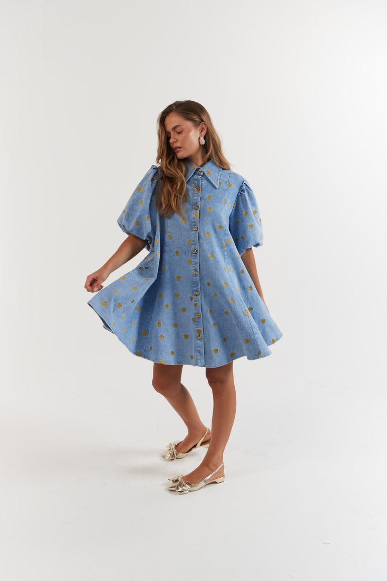 Woman wearing a blue denim dress with gold hearts