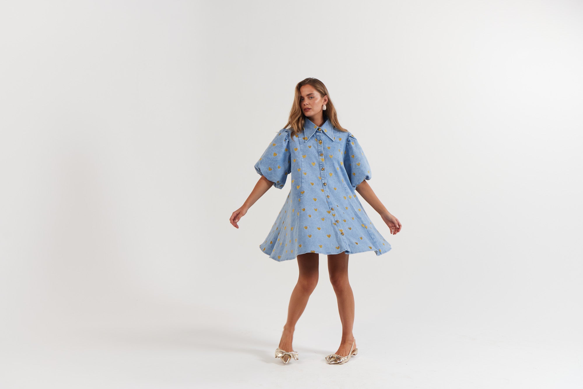 Woman wearing a blue denim dress with gold hearts