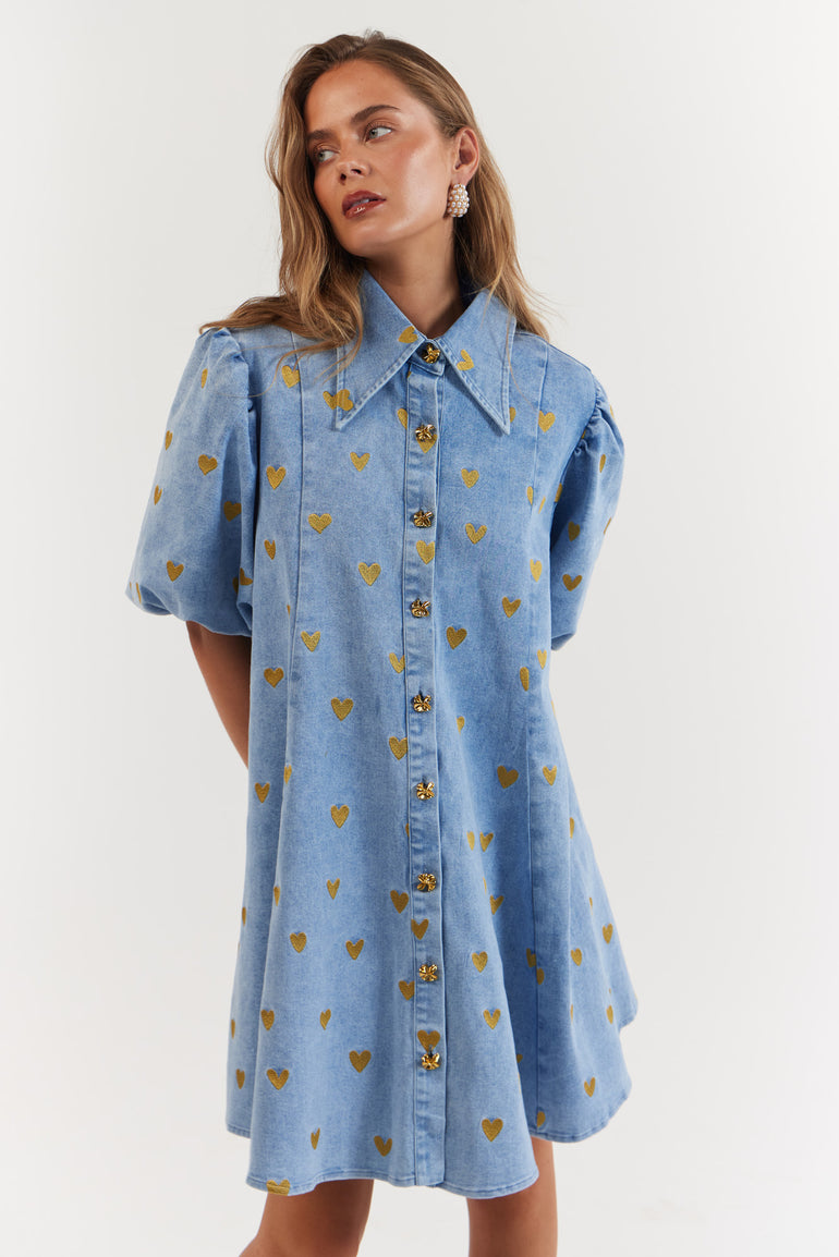 Woman wearing a blue denim dress with gold heart pattern