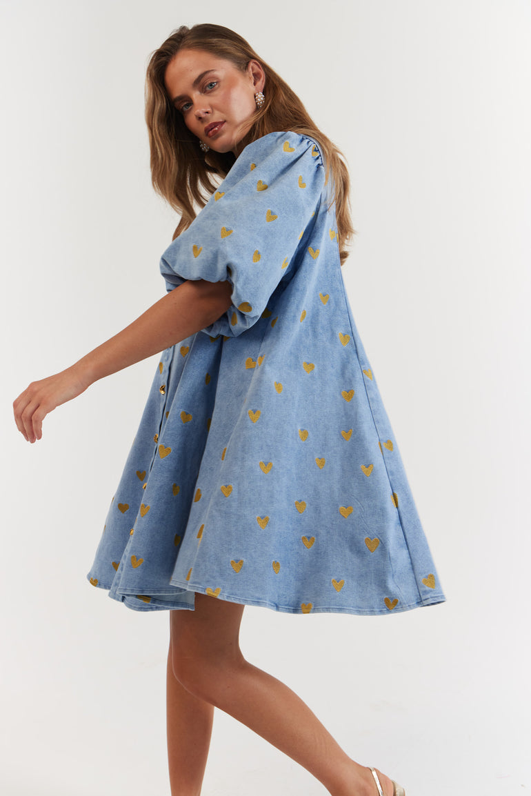Woman wearing a blue denim dress with gold hearts