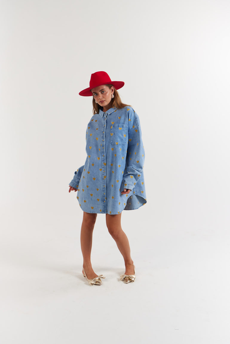 Woman wearing a blue Denim Hearts patterned dress and red hat