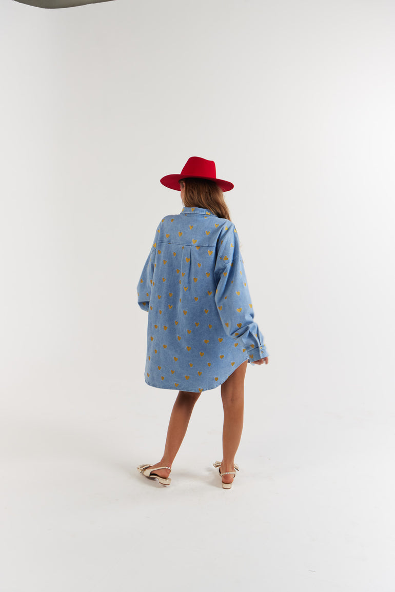 Lady wearing a blue denim coat with gold heart pattern and a red hat