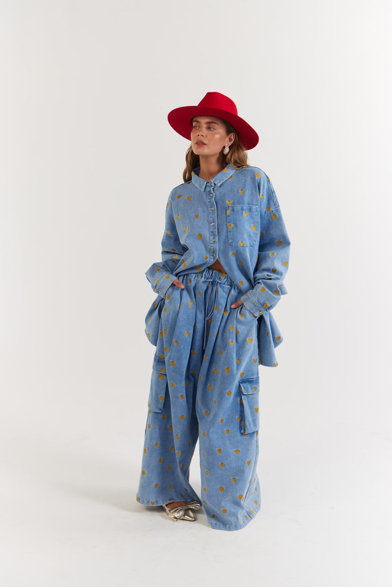 Lady wearing a blue denim, gold heart patterned outfit with a red hat