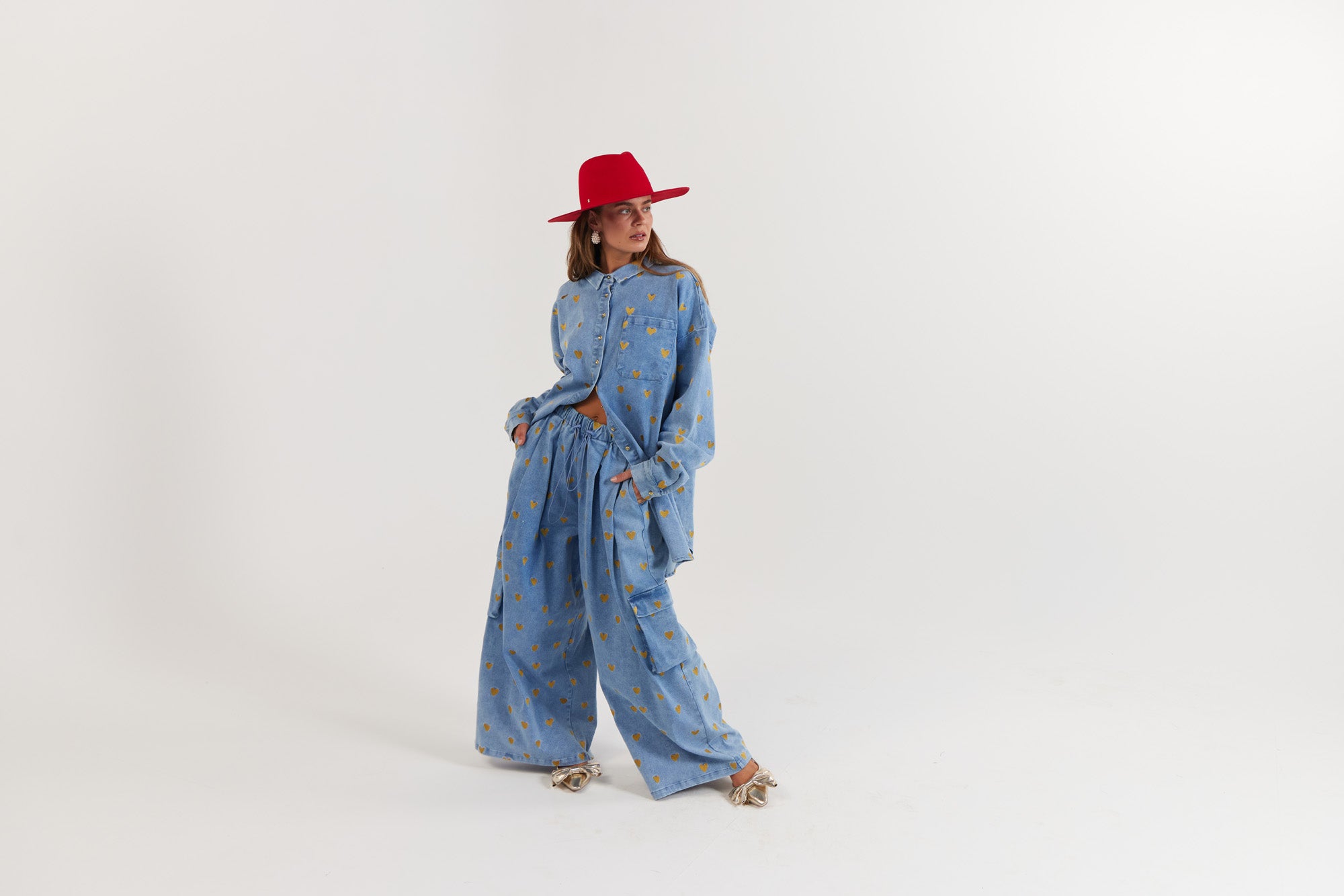 Woman wearing a blue denim outfit with gold hearts and a red hat