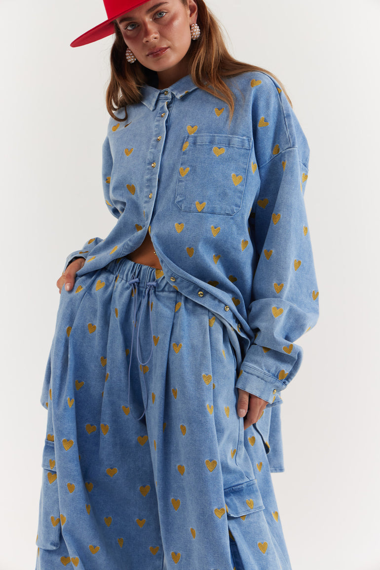 Woman wearing a blue denim outfit with gold heart pattern