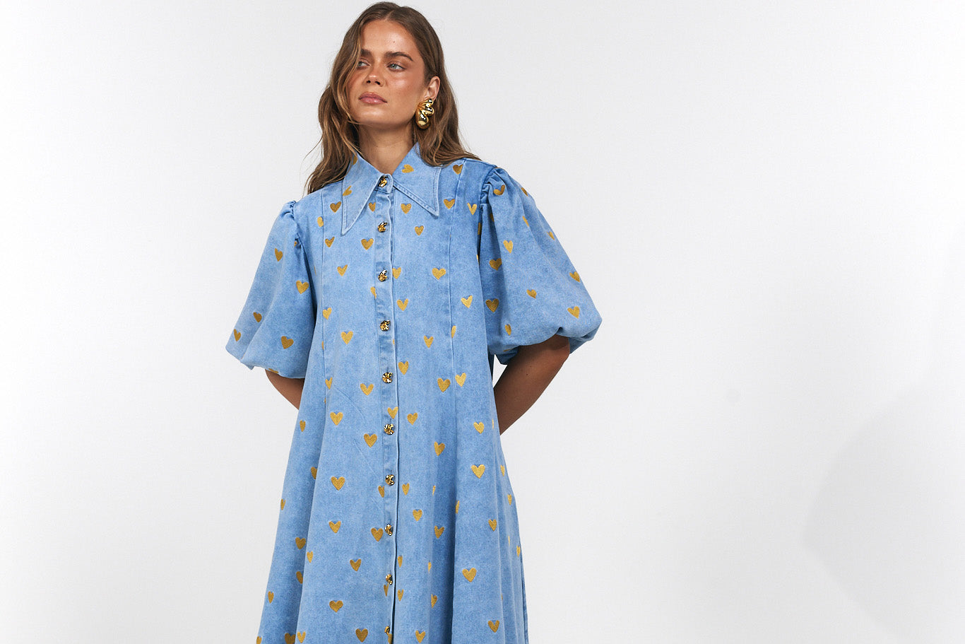 Woman wearing a blue denim dress with gold hearts