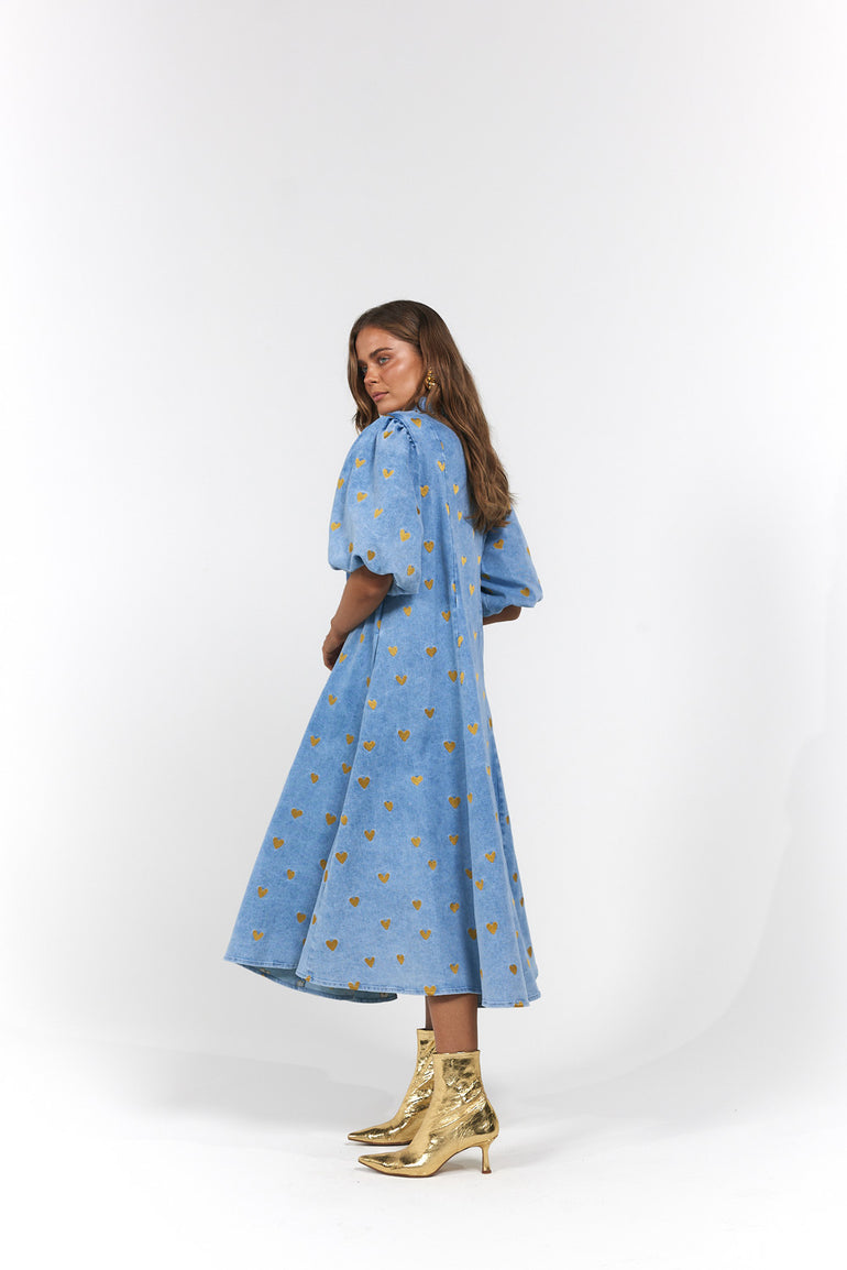 Woman wearing a blue denim dress with gold heart pattern - Denim Hearts by La Bohème