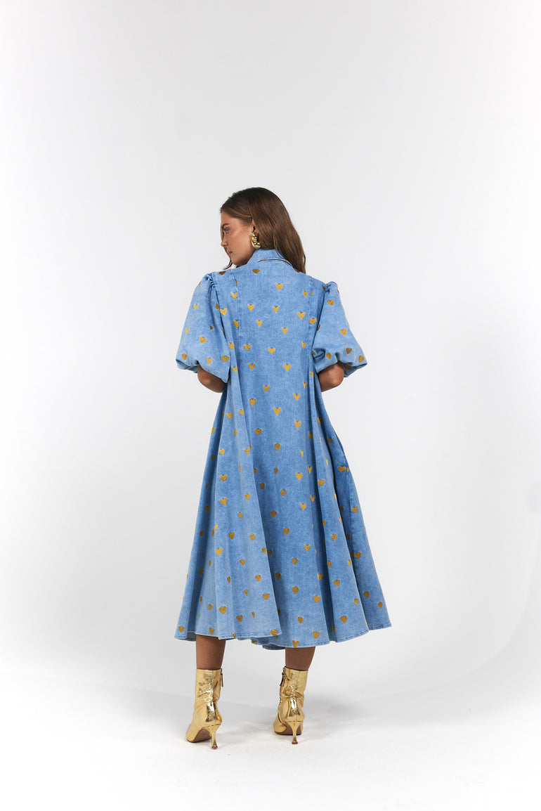 Woman wearing a blue denim dress with gold heart pattern - Denim Hearts by La Bohème