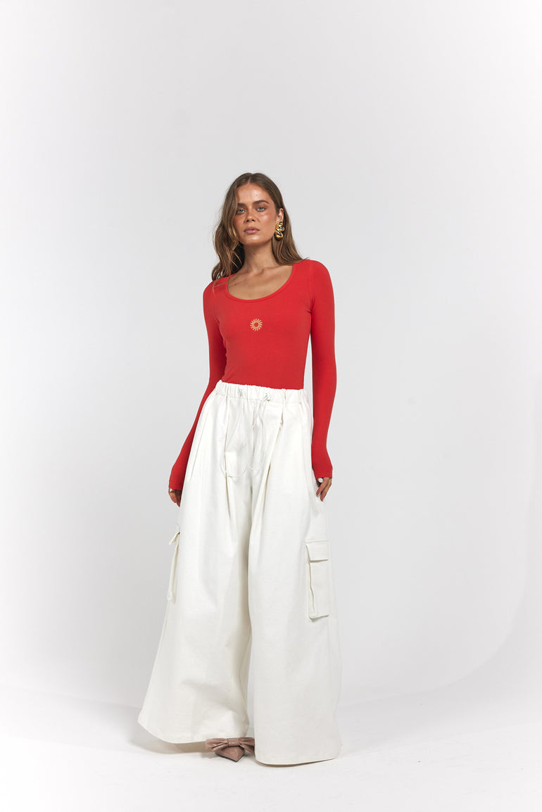 A woman modelling a red long-sleeve scoop-neck top paired with high-waisted, wide-leg white cargo pants.