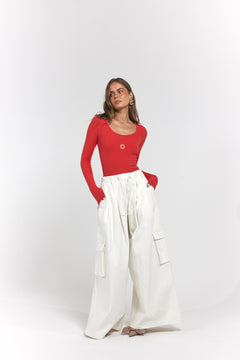 A woman modelling a red long-sleeve scoop-neck top paired with high-waisted, wide-leg white cargo pants.